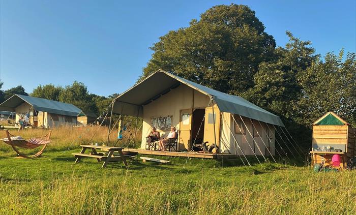 A large canvas glamping tent where you can enjoy overlooking the meadow, have a fire in the firepit or hang out in the hammock.